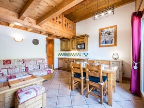 A cozy kitchen with wooden cabinets, a dining table, and chairs. - Apartment with mountain view - 3 guests (Les Menuires)
