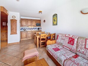 Ein gemütliches Wohnzimmer mit einer Couch und einem Essbereich mit Holzkulturen.