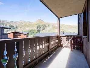 A balcony with a view of mountains, a wooden fence, and a red chair. - Spacious apartment with balcony - 4 guests (Les Menuires)