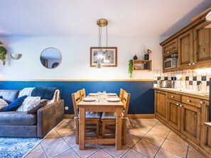 A compact living space with a dining area, kitchenette, and a sofa. - Spacious 2-room apartment with balcony, near slopes, parking included (Les Menuires)