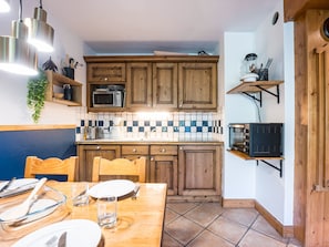 A kitchen with wooden cabinets, a microwave, a coffee maker, and a toaster. - Spacious 2-room apartment with balcony, near slopes, parking included (Les Menuires)
