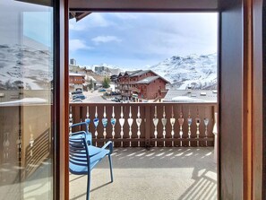 Ein Balkon mit Blick auf einen verschneiten Berg und Gebäude.