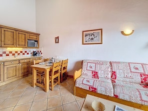 A compact living space with a kitchenette, a dining area, and a sofa. - Spacious apartment with balcony - 4 guests (Les Menuires)
