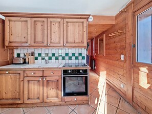 Eine Küche mit Holzschränken, einer gefliesten Spritzschutzwand und einem Herd.