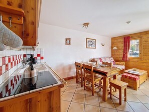 Eine kleine Küche mit Herd, Spüle und Holzschränken. Es gibt einen Essbereich mit Tisch, Stühlen und einer Couch.
