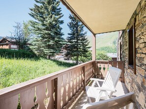 A balcony with a view of trees and a building in the background. - Spacious apartment near the slopes - 4 guests (Les Menuires)