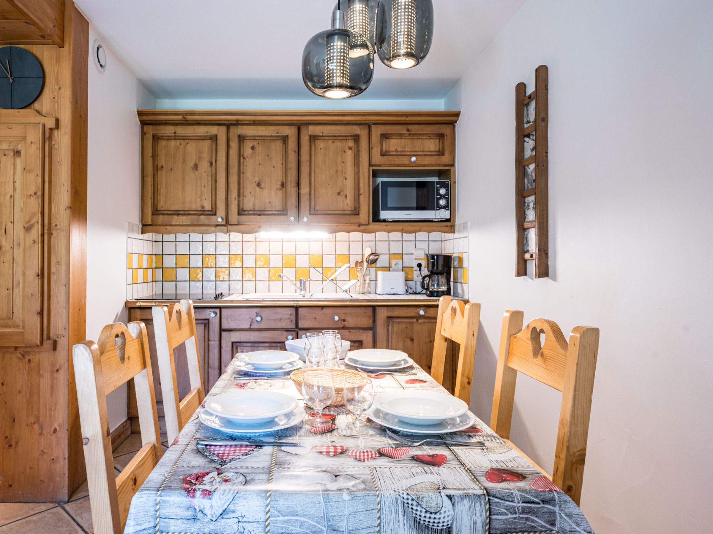 Et spiseområde med et træbord dækket til fire personer, inklusive tallerkener, glas og bestik.