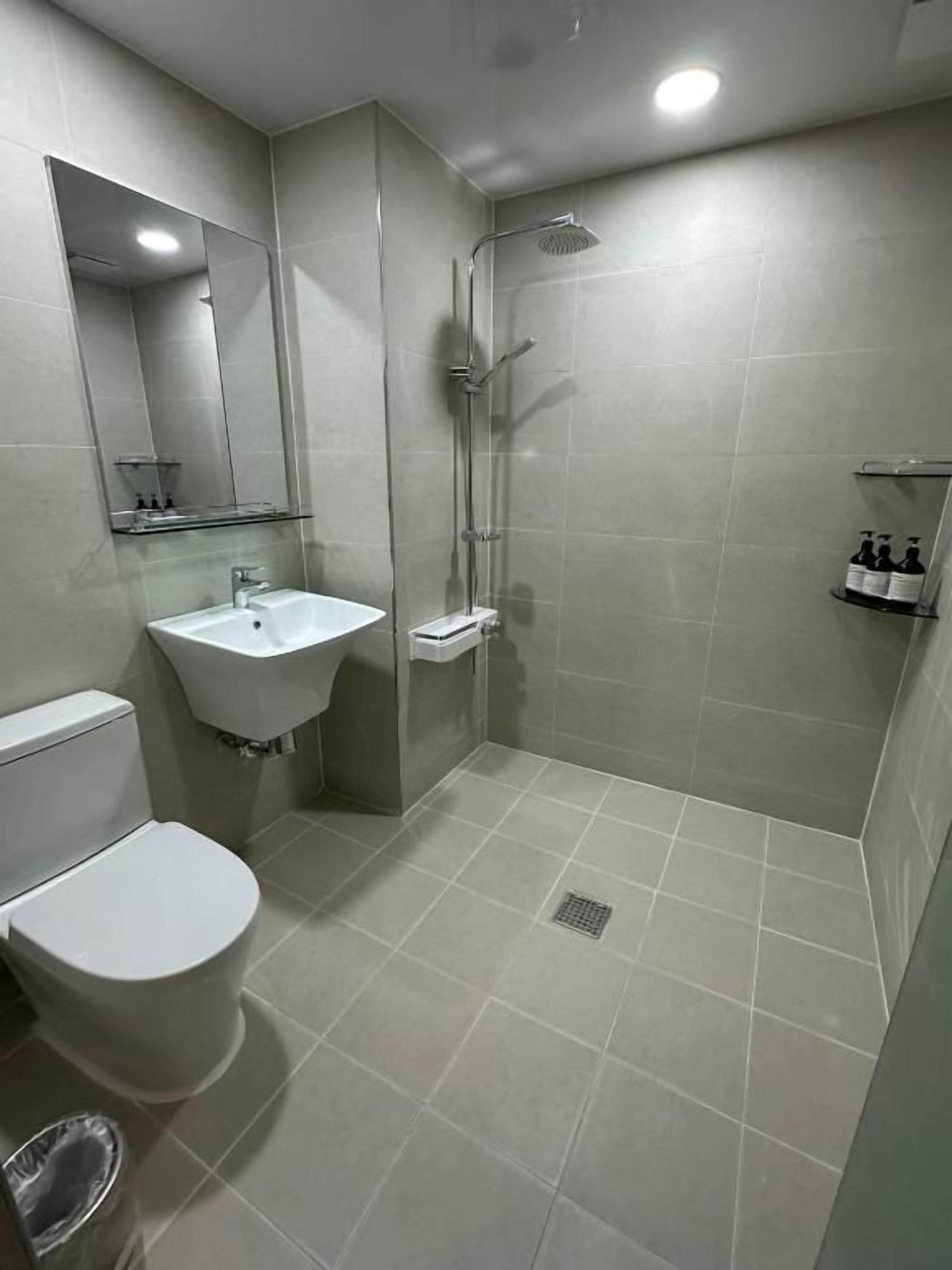 A bathroom with a toilet, sink, shower, and mirror.