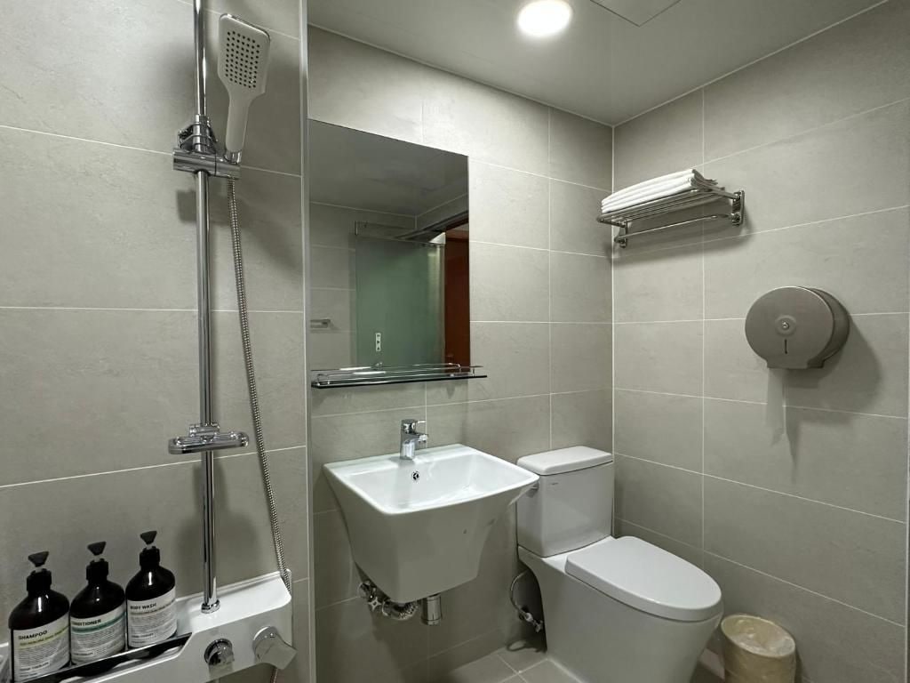 A bathroom with a shower, sink, toilet, and a towel rack.