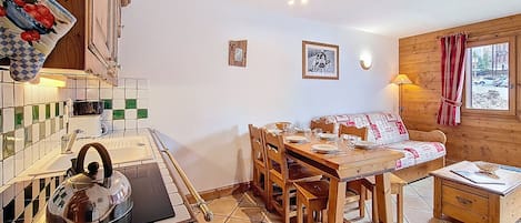 Una cocina acogedora con una mesa y sillas de madera, una tetera y un salpicadero de azulejos.