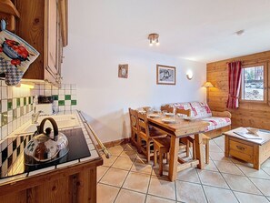 Une cuisine chaleureuse avec une table et des chaises en bois, une bouilloire et un dosseret carrelé.