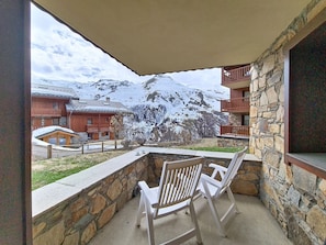 A balcony with stone walls and a view of snow-capped mountains. - Spacious apartment with terrace - 6 guests (Les Menuires)