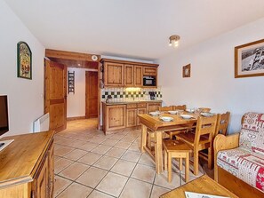 A compact living space with a kitchen, dining area, and a sofa. - Spacious apartment with terrace - 6 guests (Les Menuires)