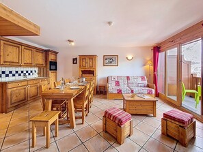 Una cocina acogedora con armarios de madera, una mesa de comedor preparada para cuatro personas y un sofá con cubierta acolchada.