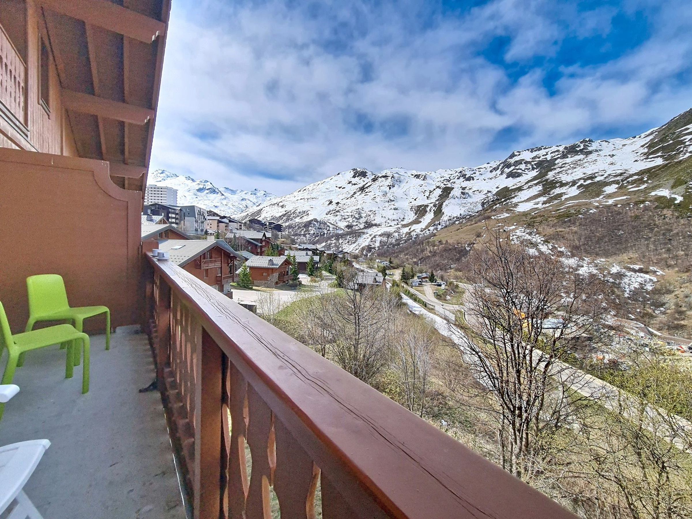 Uma varanda com vista para uma montanha coberta de neve e uma aldeia lá embaixo.