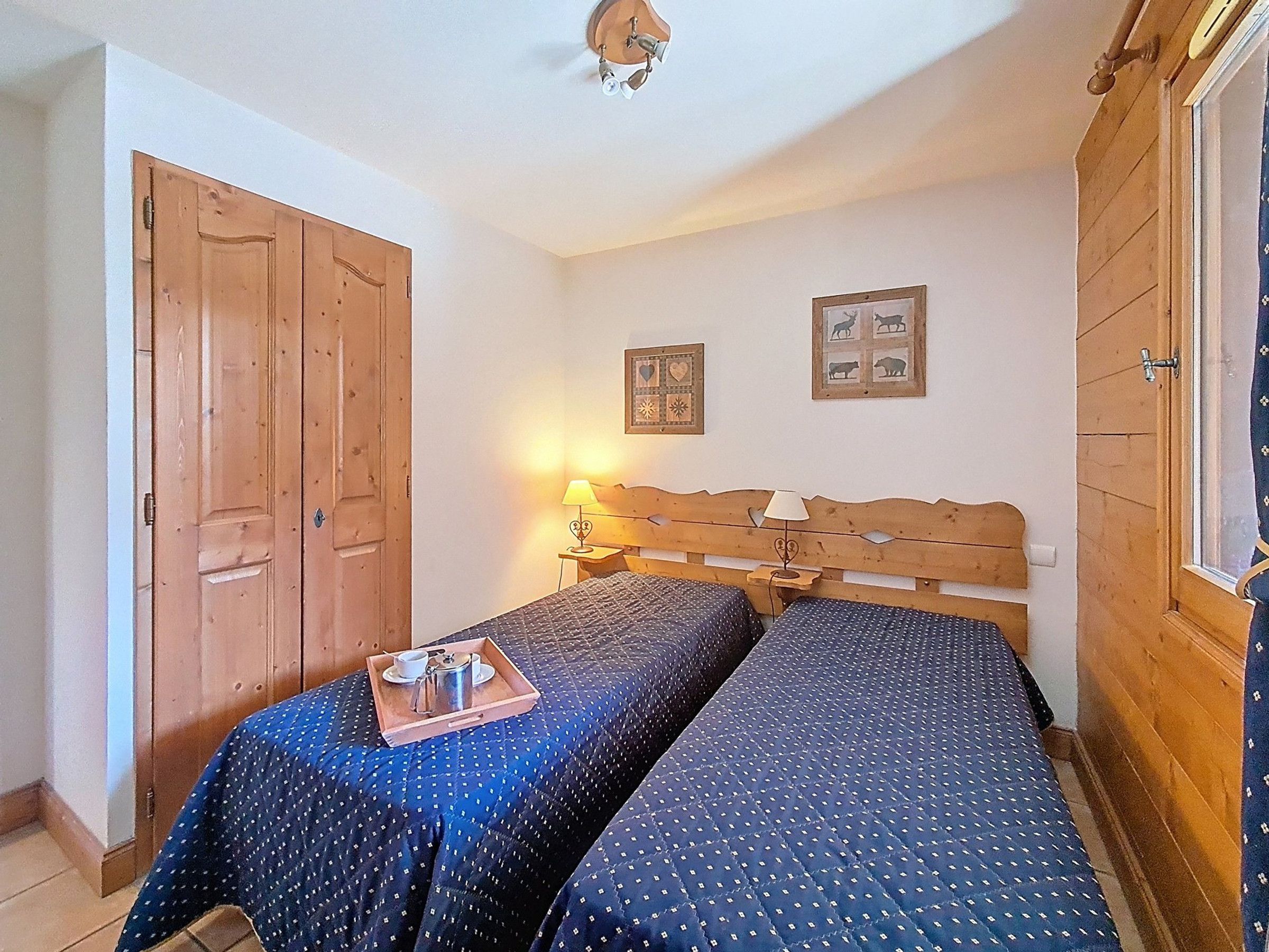 Una habitación con dos camas, un armario de madera y una lámpara de pared.