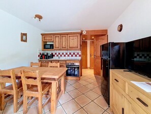 Une cuisine compacte dotée de meubles en bois, d’un four à micro-ondes, d’une cuisinière et d’un coin repas avec des chaises en bois.