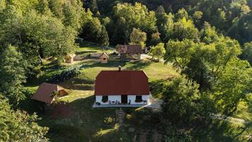 Una casa rural con techo rojo, rodeada de árboles y un pequeño jardín.