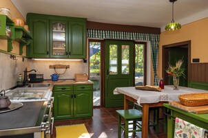 Una cocina con armarios verdes, una mesa de madera y una ventana con vista a la vegetación.