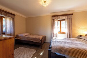 Un dormitorio con dos camas individuales, un aparador de madera, una mesita de noche y una ventana con cortinas.