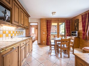 A wooden interior with a kitchen, dining area, and a view of the outdoors. - Cozy apartment - 4 guests (Les Menuires)