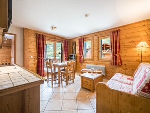 Een houten interieur met een eethoek, een bank en een televisie.