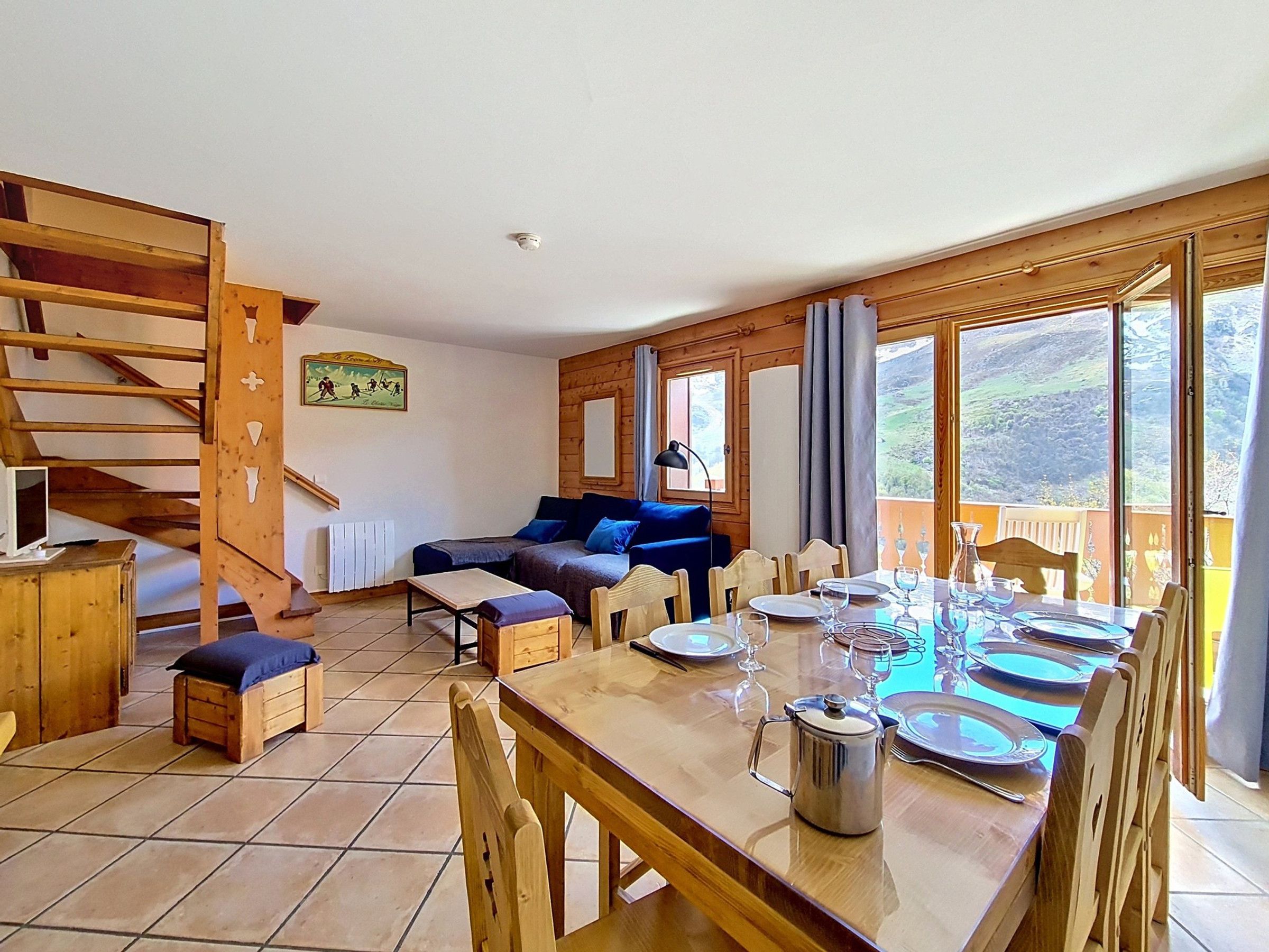 A dining area with a wooden table set for a meal, a sofa, and a staircase.