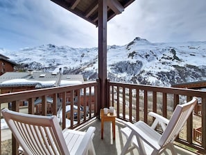 A wooden balcony with white chairs and a table, overlooking a snowy mountain landscape. - Bright apartment with balcony - 4 guests (Les Menuires)
