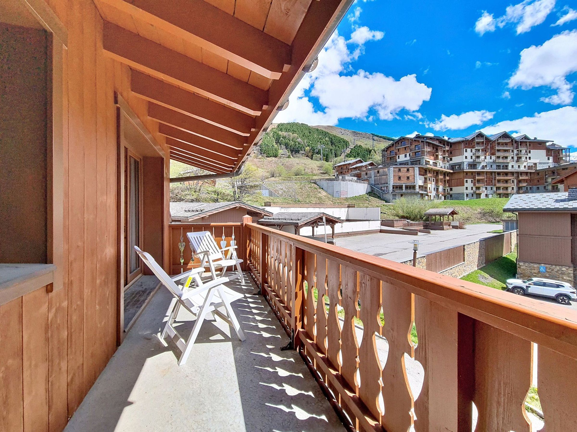 Un balcon en bois offrant une vue sur une montagne et un immeuble à plusieurs étages.