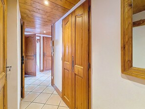 A hallway with wooden doors and a tiled floor. - Spacious apartment near slopes - 6 guests (Les Menuires)