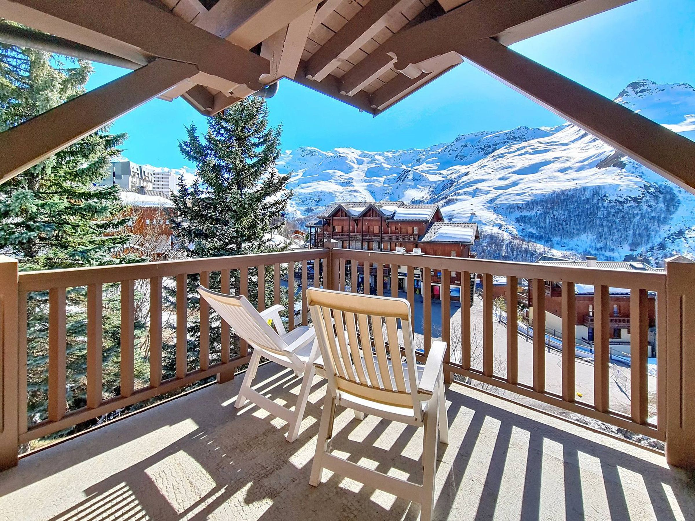 A balcony with a view of snow-covered mountains and a wooden building in the background.