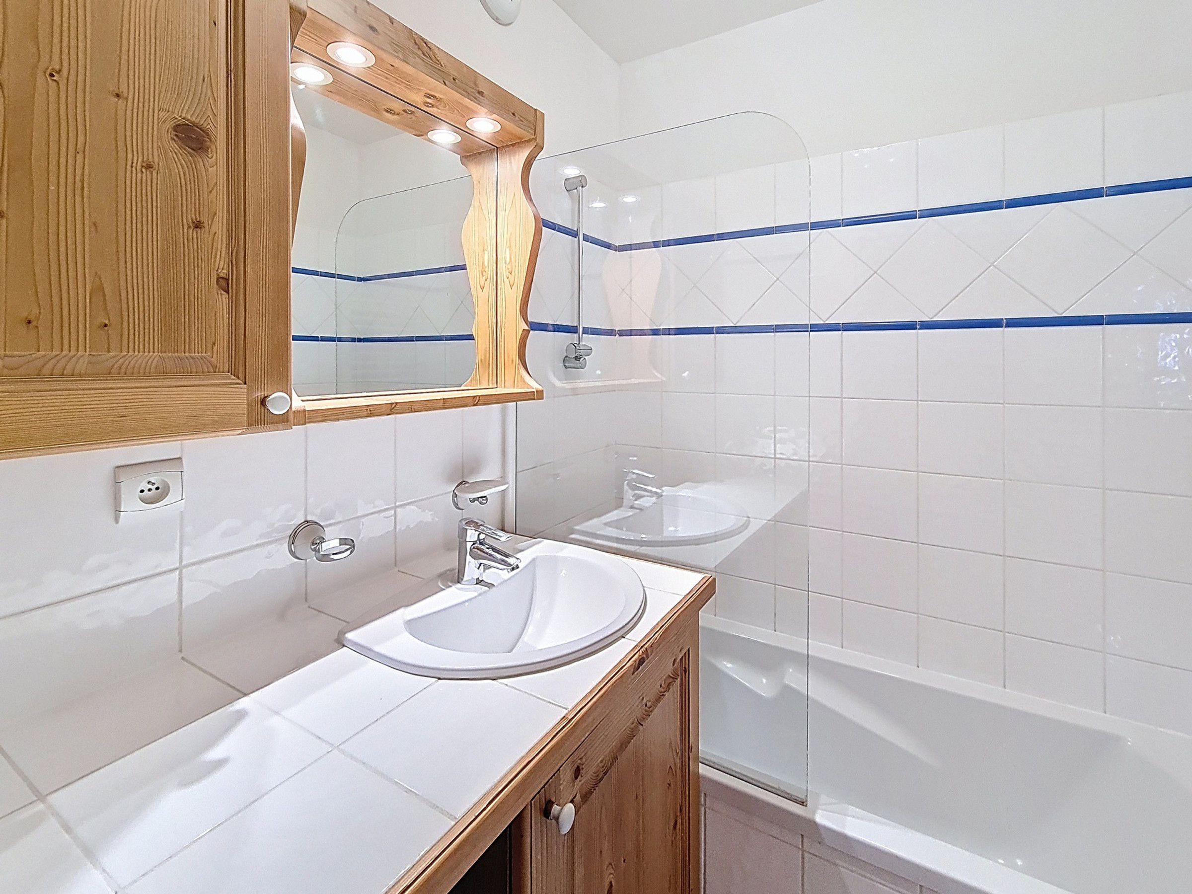 Une salle de bain avec un meuble-lavabo en bois, un miroir, un lavabo et une baignoire.