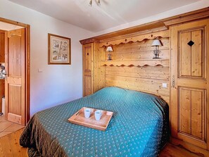 Ein Schlafzimmer mit einem hölzernen Kopfteil, einem Bett mit einer grünen Steudecke, einem Tablett mit Tassen und einer Untertasse sowie einem gerahmten Bild an der Wand.