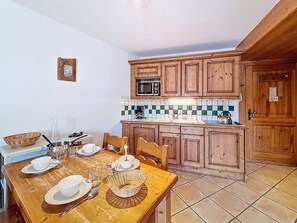 A kitchen with wooden cabinets, a microwave, and a tiled backsplash. - Apartment near slopes, balcony - 6 guests (Les Menuires)