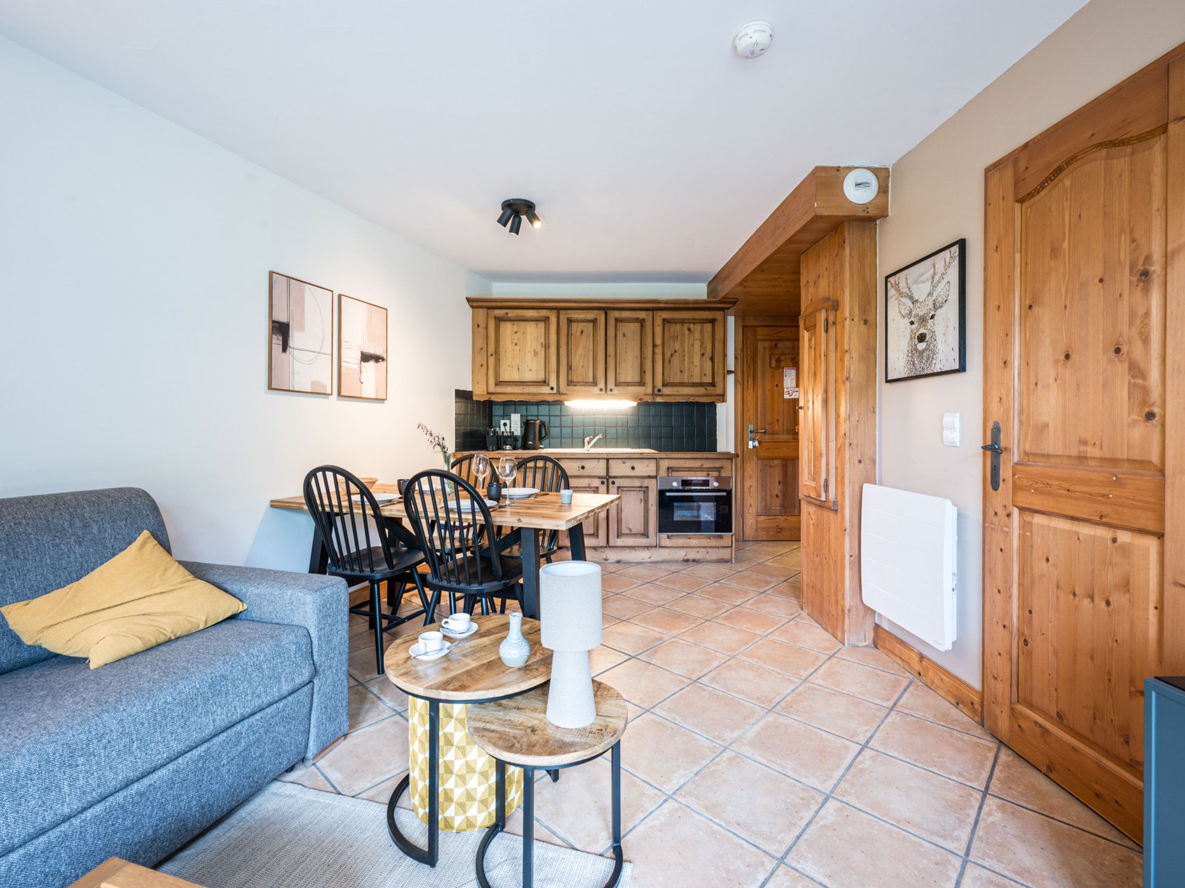 Een compacte leefruimte met een kitchenette, een eethoek en een bank.