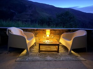 An outdoor seating area with two chairs and a table, a stone wall, and a view of hills. - Spacious apartment, terrace, pets welcome - 4 guests (Les Menuires)