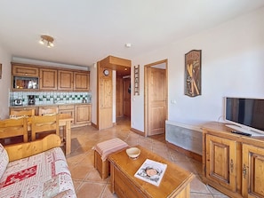 A cozy living room with a wooden sofa, a coffee table, and a television. - Pleasant apartment - 4 guests (Les Menuires)
