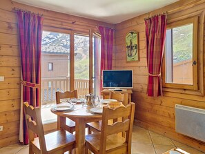 Ein Holzinterieur mit einem runden Esstisch, Stühlen, einem Fernseher und einer Heizung.