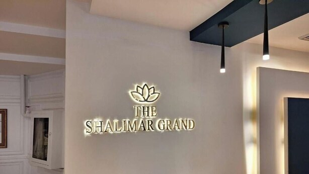 A reception area with a sign reading 'THE SHALIMAR GRAND' and a lotus symbol above the text.