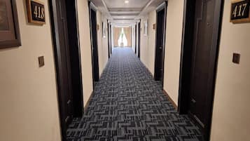A hotel hallway with carpeted floors, doors numbered 418 and 417, and a view into a room at the end.