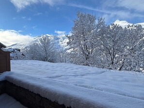 Winterliche Landschaft mit einem Berg im Hintergrund und einem Gebäude mit verschneitem Dach.