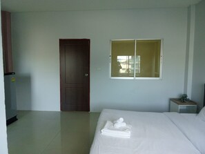 A hotel room with a bed, a window, a door, and a small bedside table with a plant. - bed room with full facture nd air-condition (Bang Lamung District, Chon Buri Province)