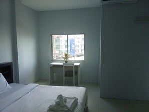 A hotel room with a bed, a desk, and a window with a view of buildings. - bed room with full facture nd air-condition (Bang Lamung District, Chon Buri Province)