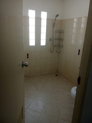 A small, tiled bathroom with a shower, a toilet, and a window. - bed room with full facture nd air-condition (Bang Lamung District, Chon Buri Province)