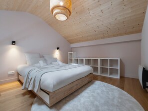 A bedroom with a wooden ceiling, a bed with white bedding, a white wall-mounted shelf unit, and a white carpet. - Sunny loft studio, 4 guests (Montvalezan-La Rosière)