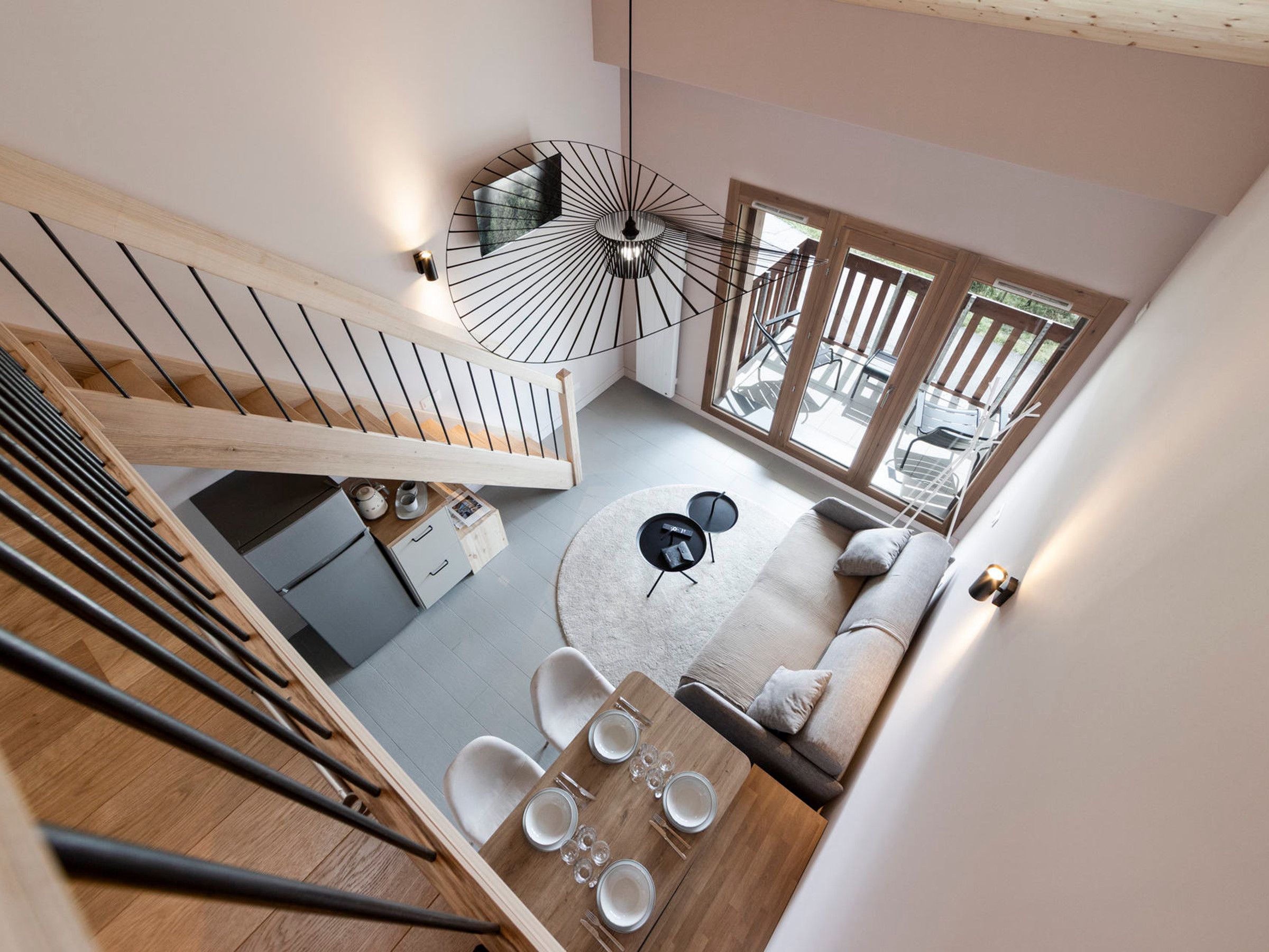 A modern interior with a staircase, a dining area, and a seating space.