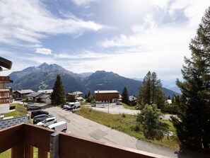 A mountain village with buildings, parked cars, and a view of the mountains. - Sunny loft studio, 4 guests (Montvalezan-La Rosière)