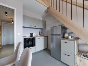 A modern kitchen with a built-in oven, a stainless steel refrigerator, and a wooden staircase. - Sunny loft studio, 4 guests (Montvalezan-La Rosière)