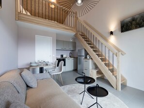A modern apartment with a loft-style ceiling, a kitchen area, a dining space, and a staircase. - Sunny loft studio, 4 guests (Montvalezan-La Rosière)