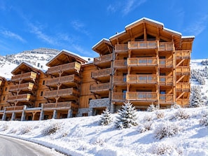 A multi-story wooden lodge with balconies, set against a snowy mountain backdrop. - Spacious apartment with view of Muzelle - 8 guests (Les Deux Alpes)